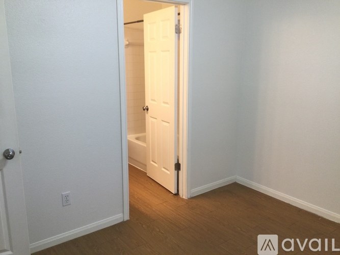 A white door is open to a room with wooden floors.