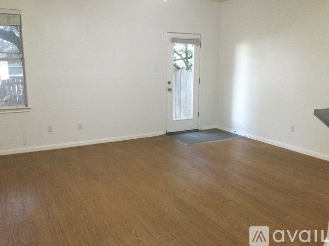 A room with wooden flooring and a door leading to a balcony.