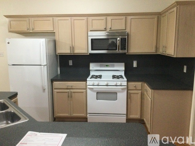 A kitchen with a white refrigerator, white stove, and wooden cabinets.