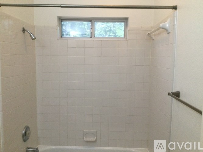 A white tiled shower with a window above it.