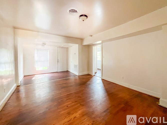 A spacious room with wooden floors and white walls.