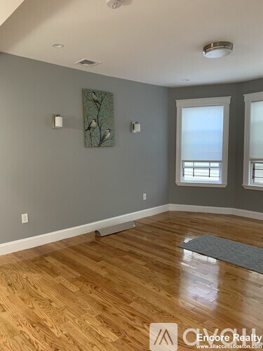 A room with wooden floors and two windows.