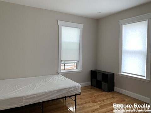 A bedroom with a bed, a window, and a black cube-shaped object.
