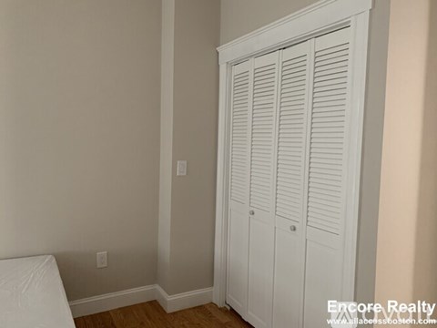 A white closet with a white mattress on the floor.