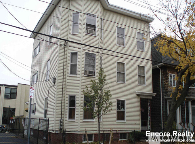 A white building with a tree in front of it.