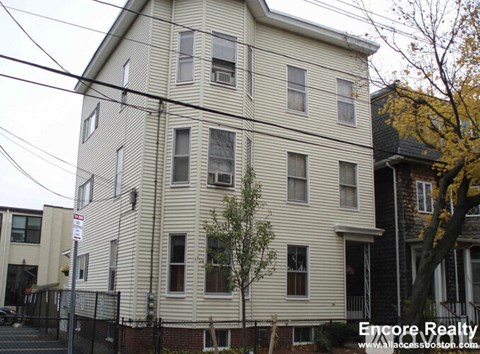 A white building with a tree in front of it.