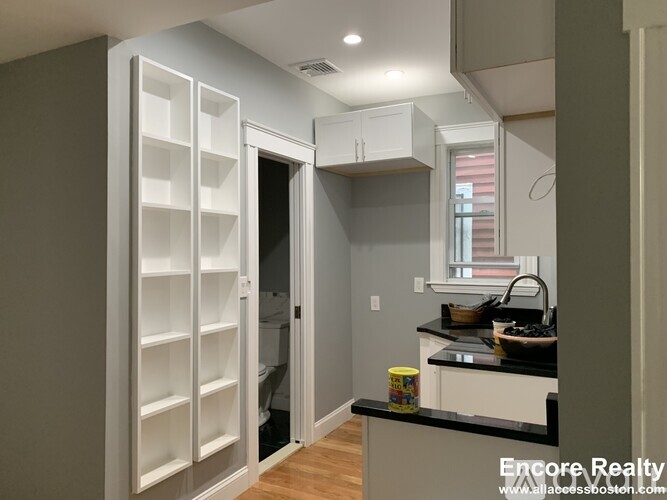 A kitchen with a black counter top and white cabinets.