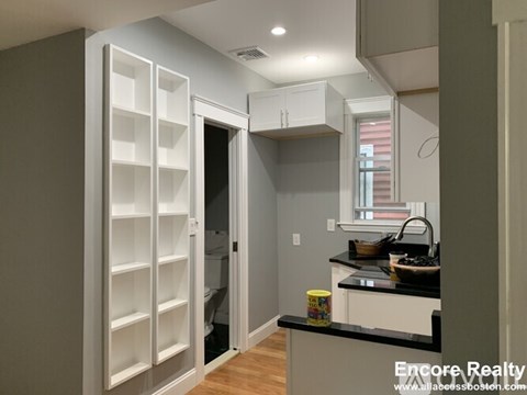 A kitchen with a black counter top and white cabinets.