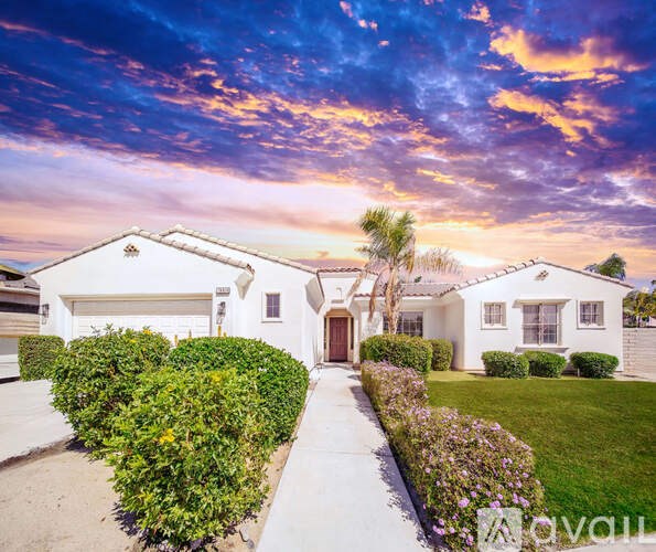 A house with a driveway and a hedge in front of it.