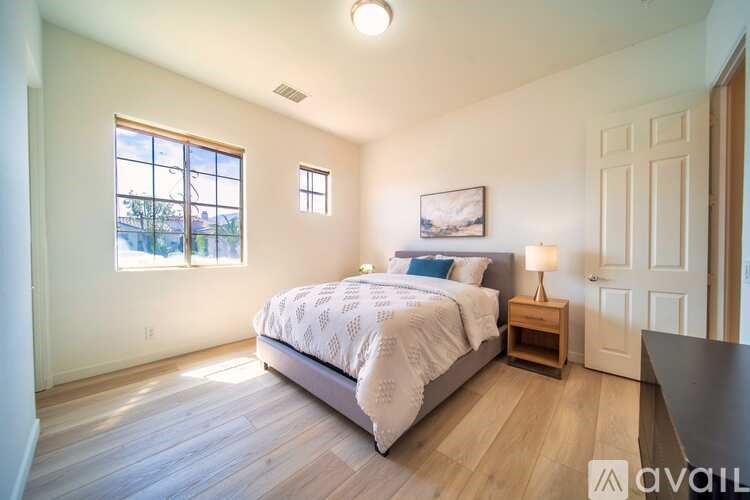 A bedroom with a large bed, a window, and a painting on the wall.