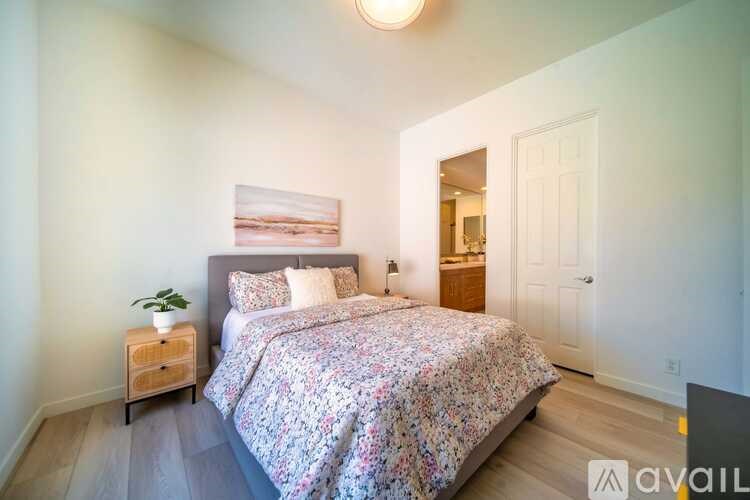 A bedroom with a floral bedspread and a painting on the wall.