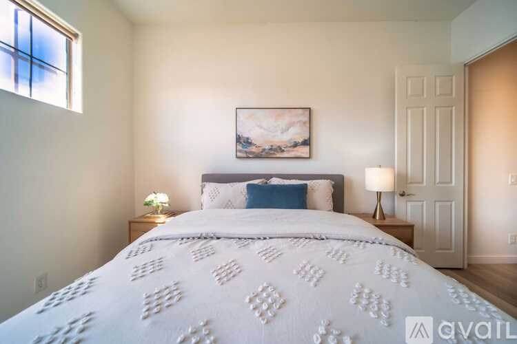 A bedroom with a large bed and a painting on the wall.