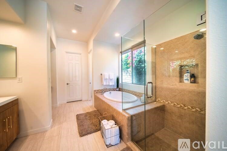 A bathroom with a glass shower door and a brown rug on the floor.