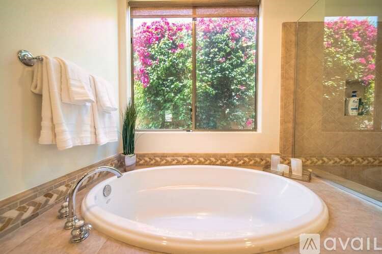 A bathroom with a tub and a window with pink flowers.