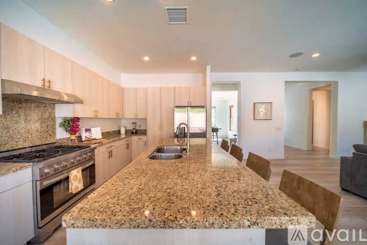 A kitchen with granite countertops and a dining area with chairs.