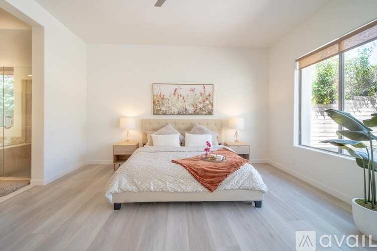 A bedroom with a large bed and a painting on the wall.