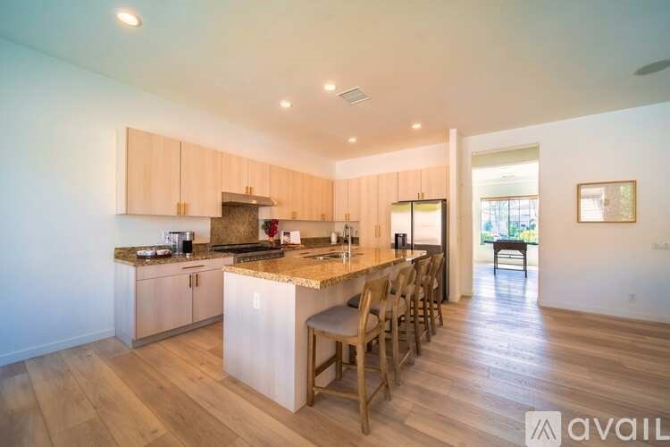 A kitchen with wooden floors and a center island with chairs.