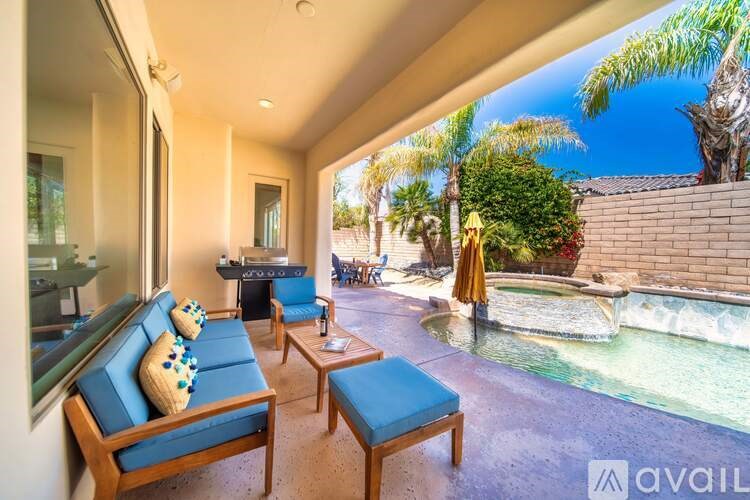 A sunny day at a poolside patio with a blue couch and a yellow umbrella.