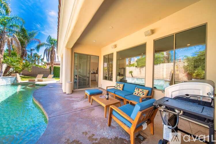 A poolside patio with a chaise lounge and a table.