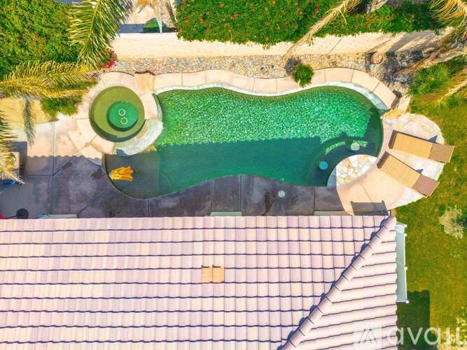 A swimming pool with a green tiled edge and a stone border.