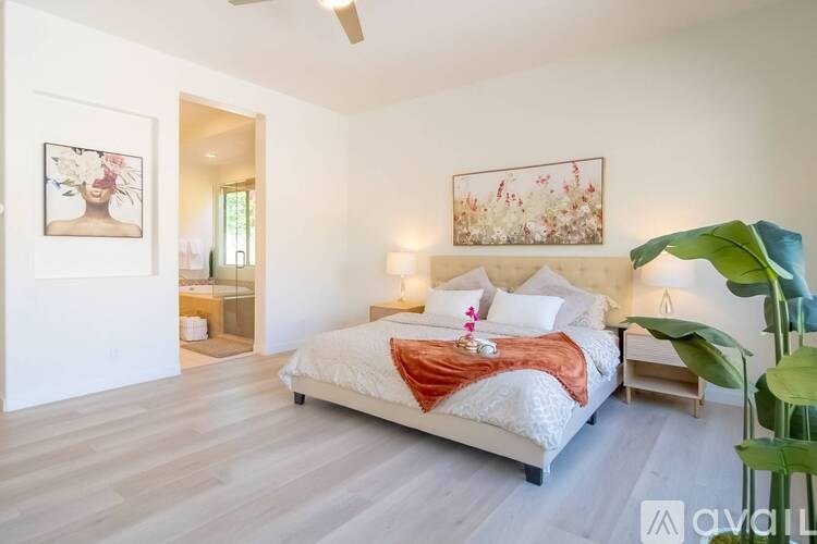 A bedroom with a bed, a chair, and a painting on the wall.