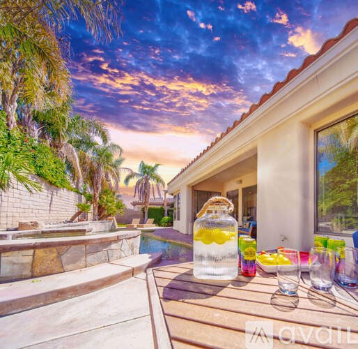 A table with drinks and a pitcher of lemonade sits on a patio.