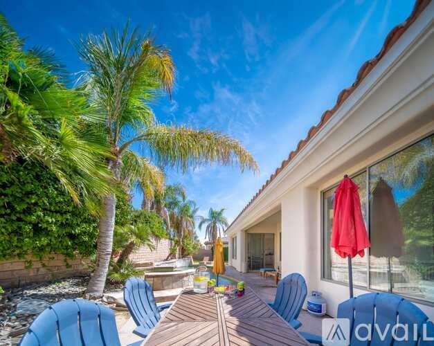 A sunny day at a house with a pool and a red umbrella.