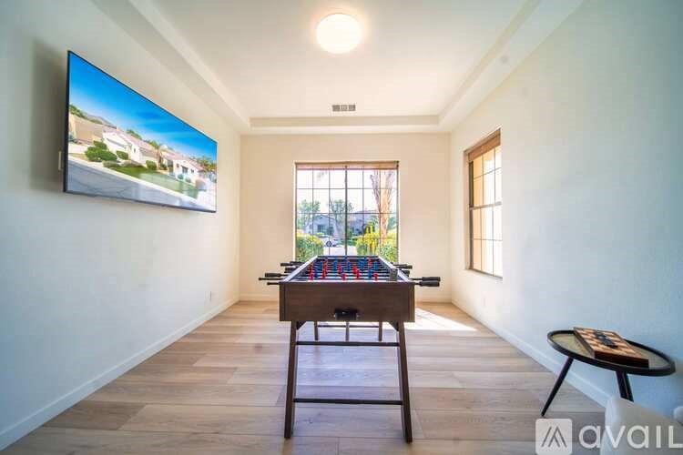 A room with a foosball table and a TV mounted on the wall.