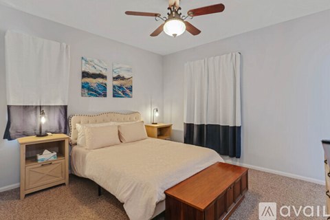 A bedroom with a bed, nightstand, and a ceiling fan.