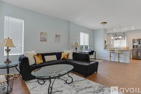 A living room with a black couch and a glass coffee table.