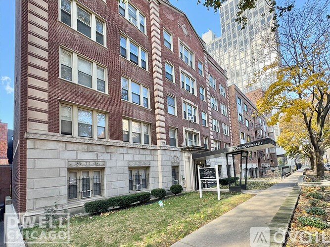 A red brick building with a white sign in front of it.