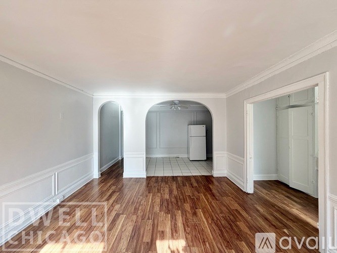 A white room with a wooden floor and a doorway leading to another room.