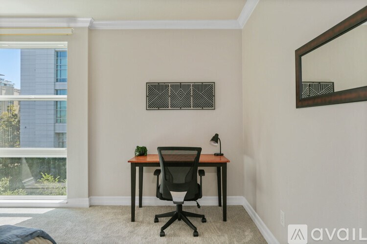 A room with a desk and chair in front of a window.