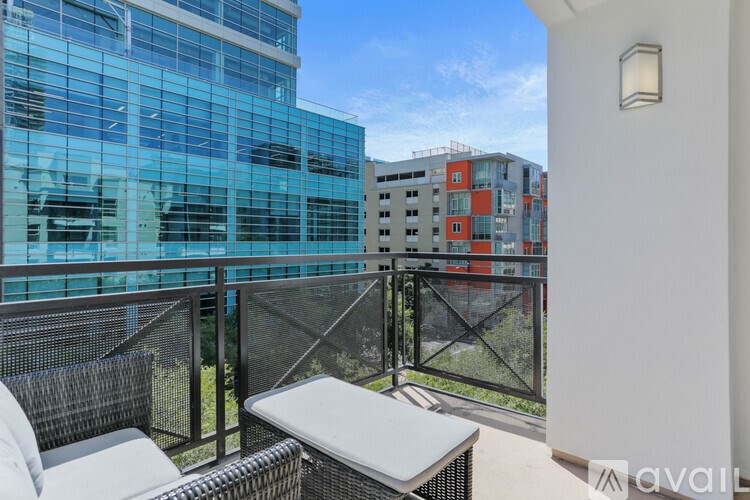 A balcony with a white table and chairs overlooks a cityscape.
