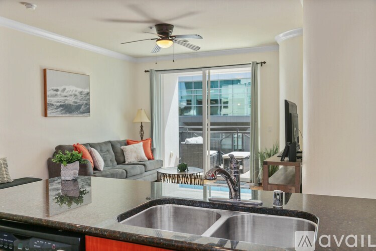 A modern kitchen with a stainless steel sink and a ceiling fan.