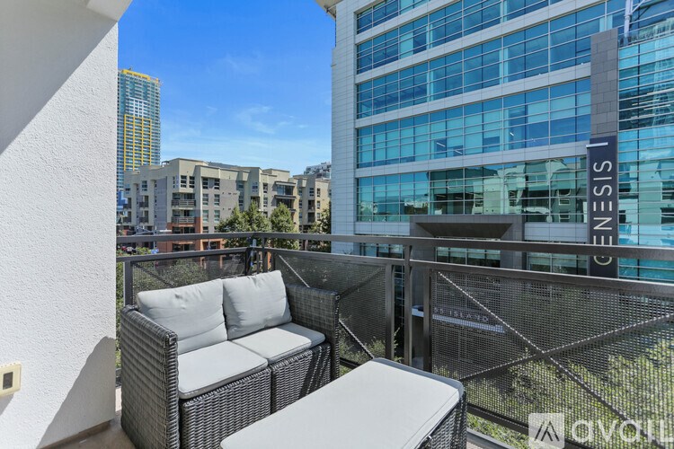 A balcony with a couch and a table is overlooking a cityscape.