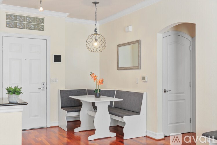 A dining area with a white table and grey bench.