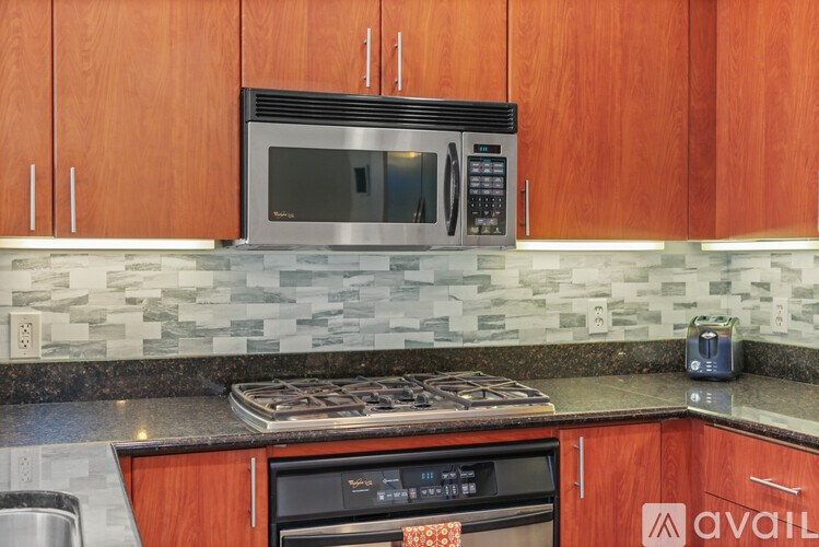A kitchen with wooden cabinets and a black microwave above the stove.