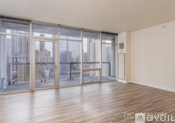 A spacious room with wooden floors and large windows overlooking a cityscape.