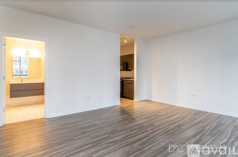 A spacious room with wooden flooring and a doorway leading to another room.