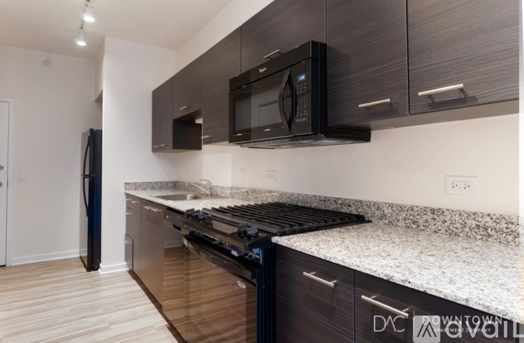 A modern kitchen with a granite countertop and dark wood cabinets.
