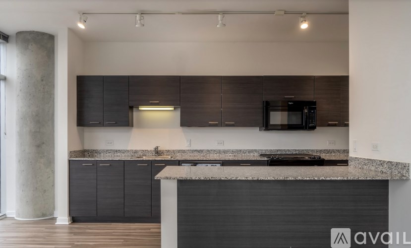 A modern kitchen with dark cabinets and a granite countertop.