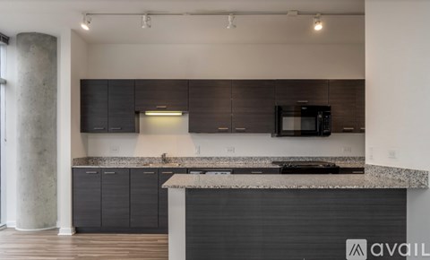 A modern kitchen with dark cabinets and a granite countertop.