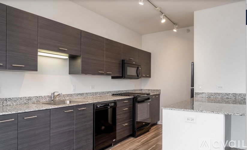 A kitchen with dark brown cabinets and black appliances.