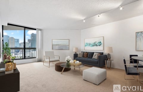A living room with a large window, a couch, a chair, a coffee table, and a painting on the wall.