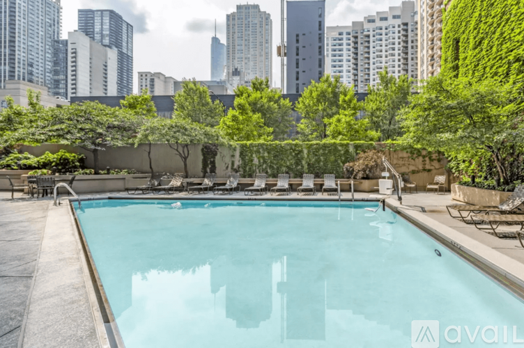 A pool surrounded by greenery and city buildings in the background.