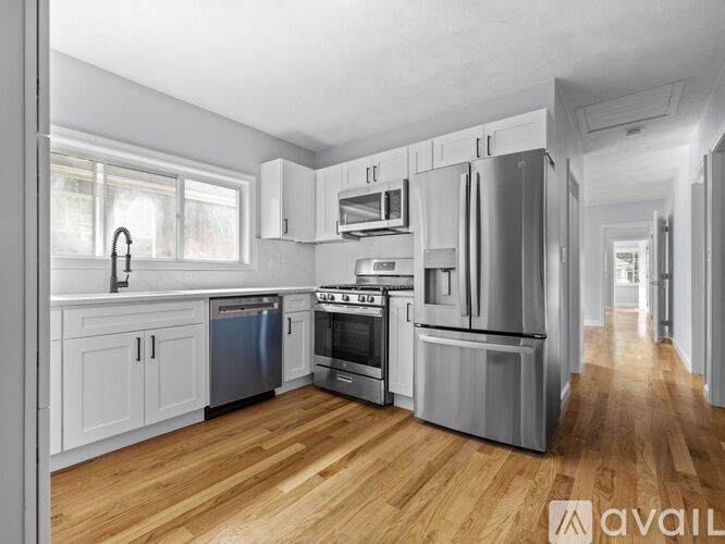 A modern kitchen with wooden floors and stainless steel appliances.