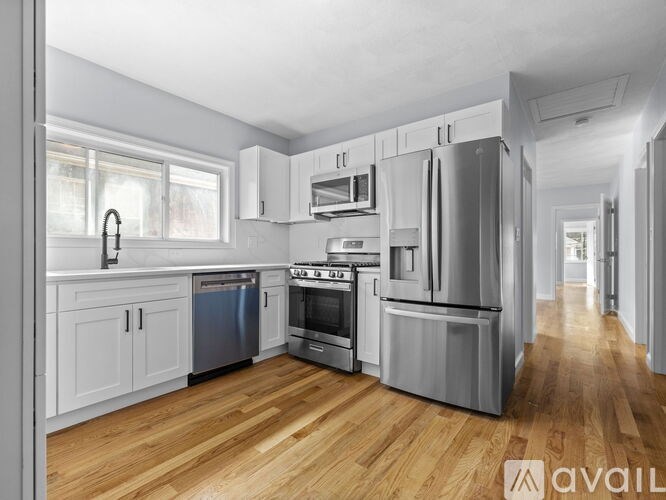A modern kitchen with wooden floors and stainless steel appliances.