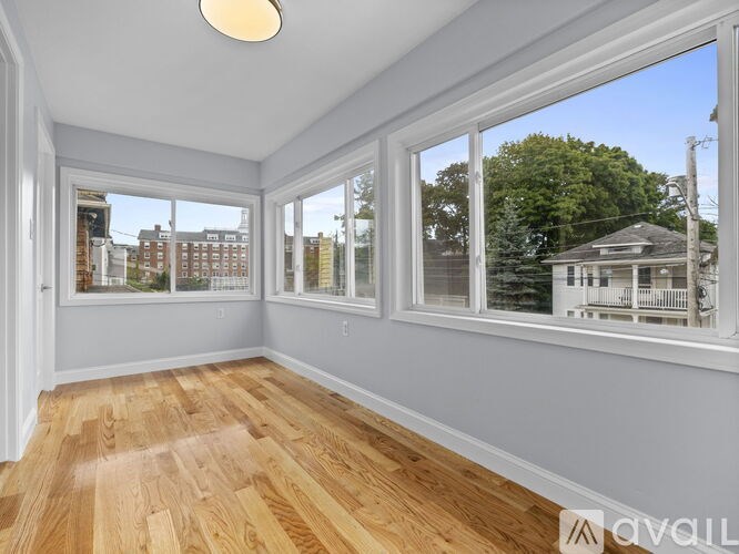 A room with wooden floors and large windows overlooking a residential area.