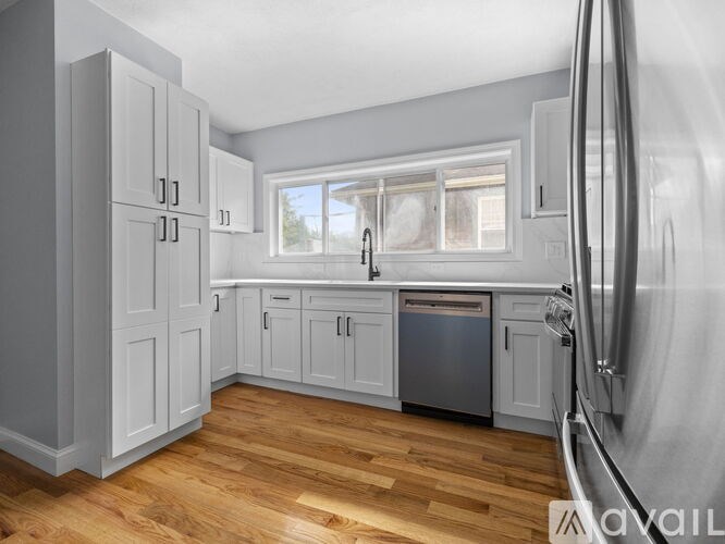 A kitchen with white cabinets and a wooden floor.